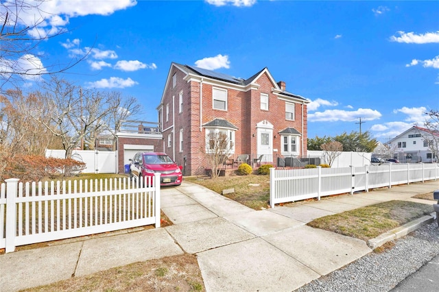 view of front of property featuring a gate, roof mounted solar panels, brick siding, and a fenced front yard