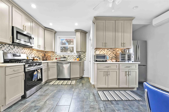 kitchen with gray cabinetry, a wall mounted AC, tasteful backsplash, stainless steel appliances, and light countertops