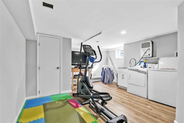 workout area with light wood-type flooring, baseboards, and separate washer and dryer