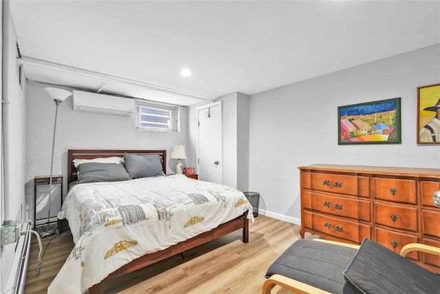 bedroom with a wall unit AC, light wood-style floors, and baseboards