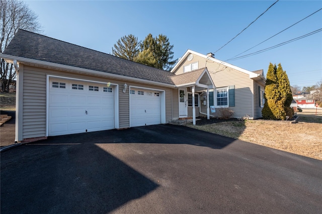 view of front facade featuring a garage, driveway, and roof with shingles