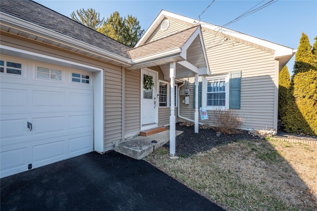 view of front of home featuring entry steps, a shingled roof, and a garage