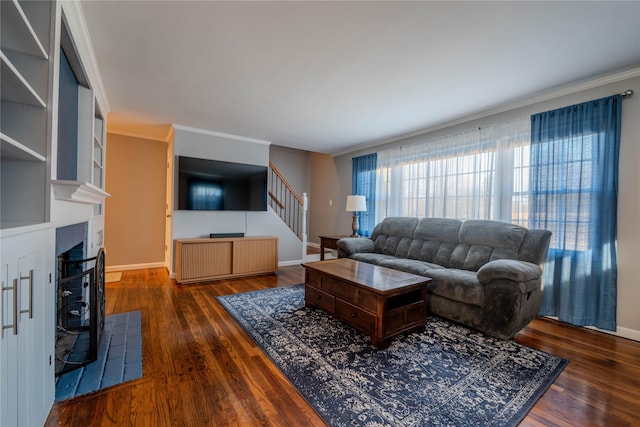 living area featuring ornamental molding, a fireplace, stairs, and wood finished floors