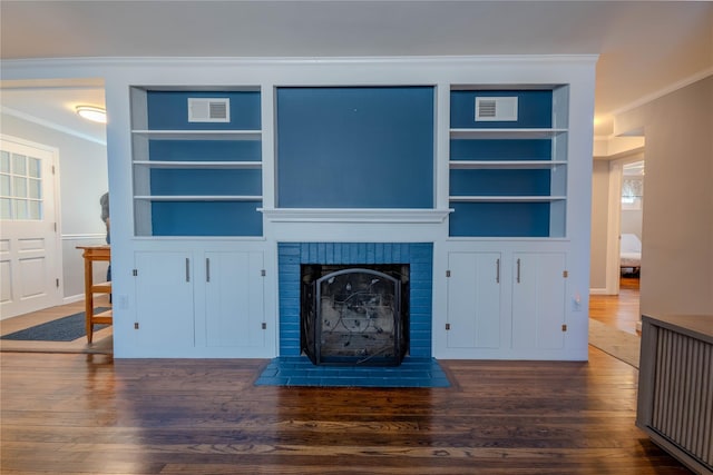 unfurnished living room with visible vents, a fireplace, crown molding, and wood finished floors