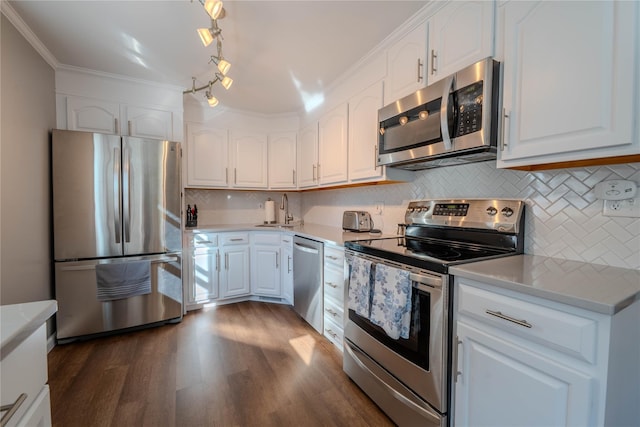 kitchen with dark wood-type flooring, a sink, appliances with stainless steel finishes, white cabinets, and crown molding