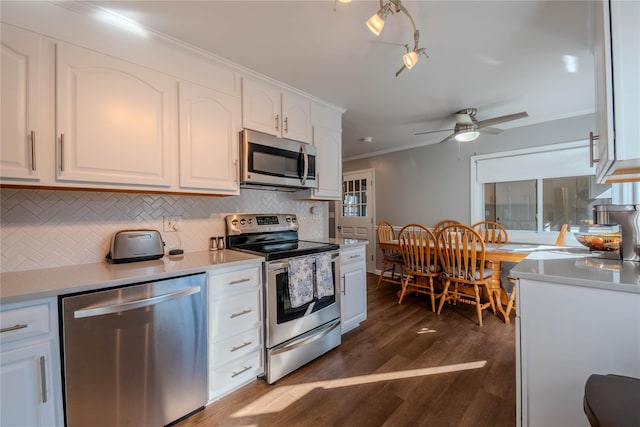 kitchen featuring dark wood finished floors, ornamental molding, decorative backsplash, white cabinets, and stainless steel appliances