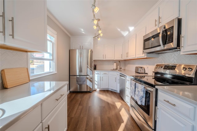 kitchen with light countertops, crown molding, appliances with stainless steel finishes, and a sink