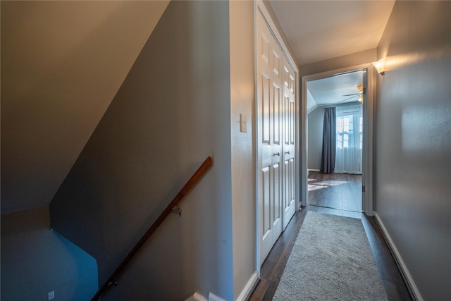 hallway featuring lofted ceiling, wood finished floors, an upstairs landing, and baseboards