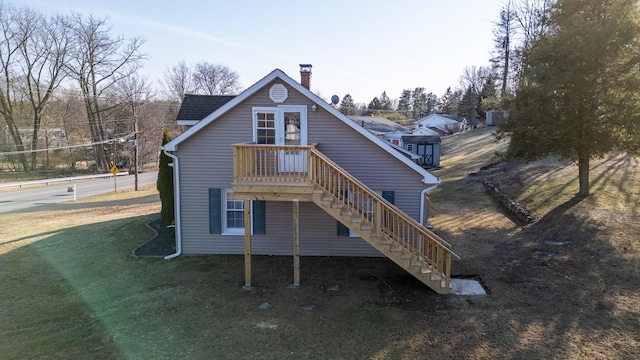 back of property featuring stairway, a yard, and a chimney