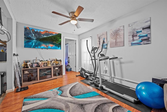 exercise room featuring ceiling fan, wood finished floors, and a textured ceiling