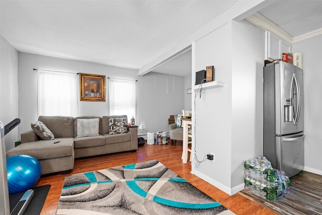 living room featuring a textured ceiling, baseboards, and wood finished floors