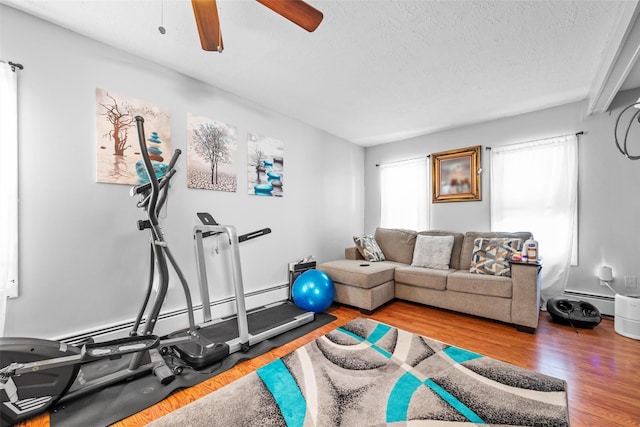 exercise area with a textured ceiling, a ceiling fan, and wood finished floors