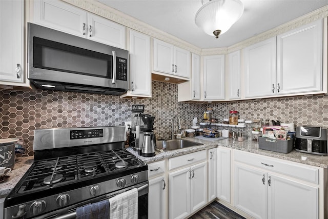 kitchen featuring a sink, stainless steel appliances, backsplash, and white cabinetry