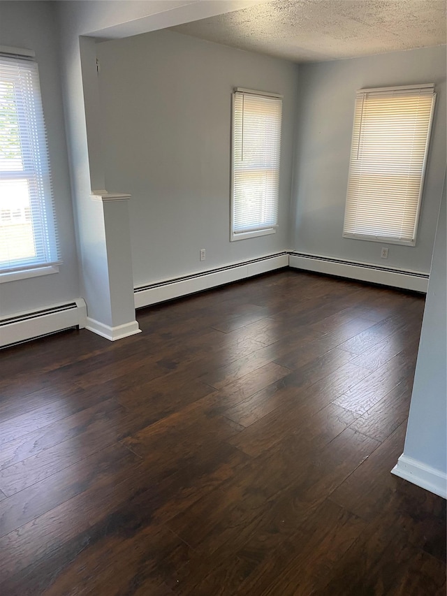 empty room with hardwood / wood-style floors, baseboards, baseboard heating, and a textured ceiling