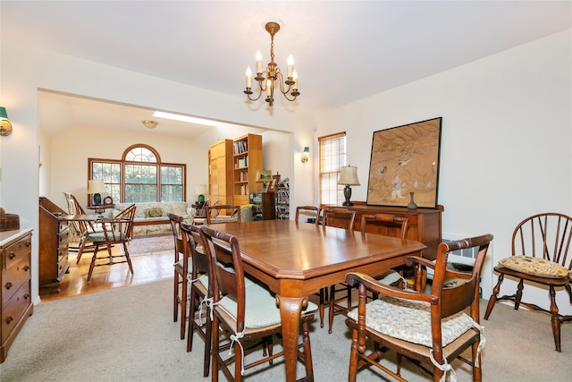 dining area with an inviting chandelier, light colored carpet, and vaulted ceiling