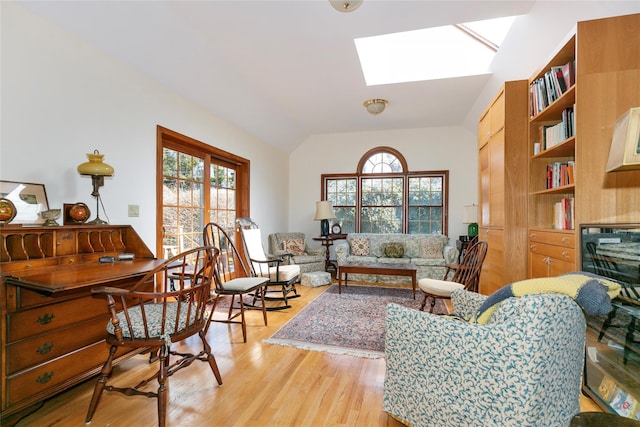 living area featuring lofted ceiling with skylight and light wood-style flooring