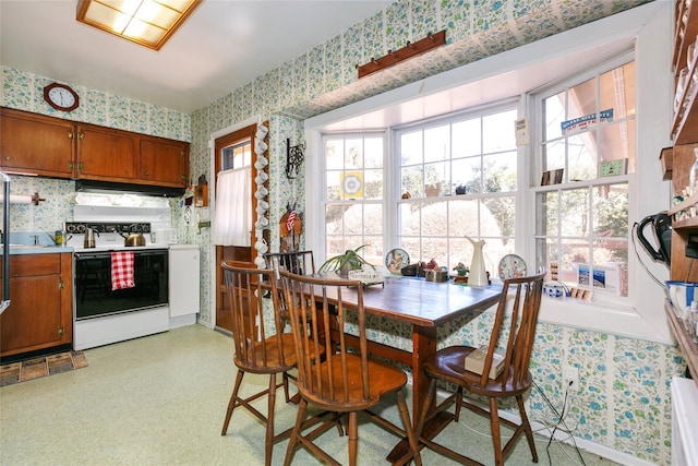 dining area with light floors and wallpapered walls