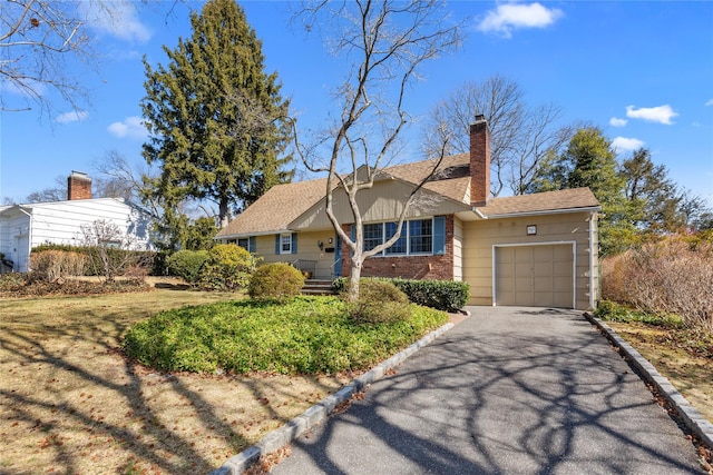 ranch-style home with brick siding, a shingled roof, a chimney, driveway, and an attached garage