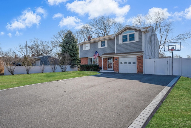 view of front of property with a front yard, a gate, fence, aphalt driveway, and brick siding