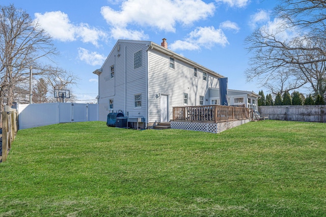 rear view of house with a fenced backyard, a lawn, and a deck