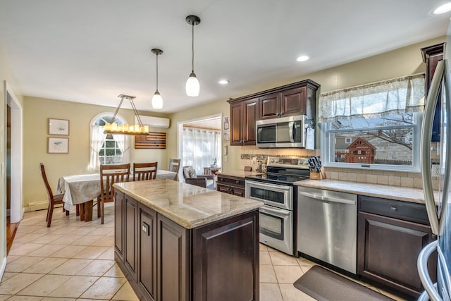 kitchen featuring decorative light fixtures, backsplash, stainless steel appliances, light tile patterned floors, and dark brown cabinets