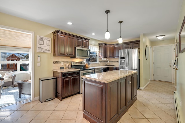 kitchen with a sink, tasteful backsplash, appliances with stainless steel finishes, light tile patterned floors, and hanging light fixtures