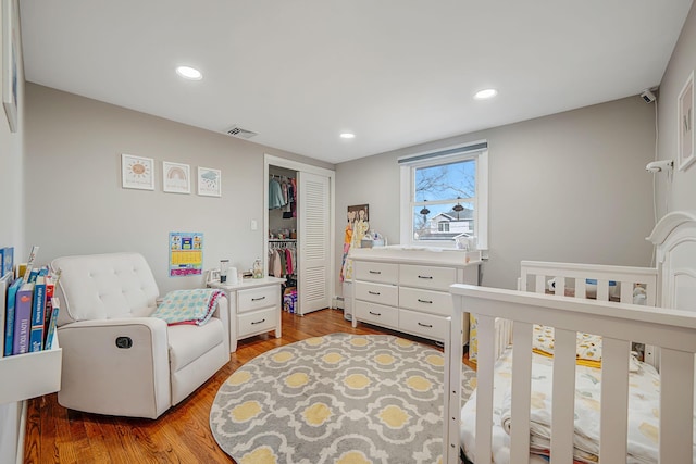 bedroom with visible vents, a crib, recessed lighting, a closet, and light wood finished floors