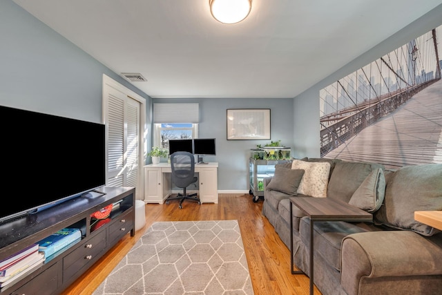 living room with baseboards, visible vents, and light wood finished floors