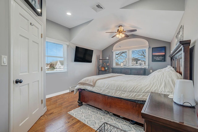 bedroom with lofted ceiling, multiple windows, wood finished floors, and visible vents