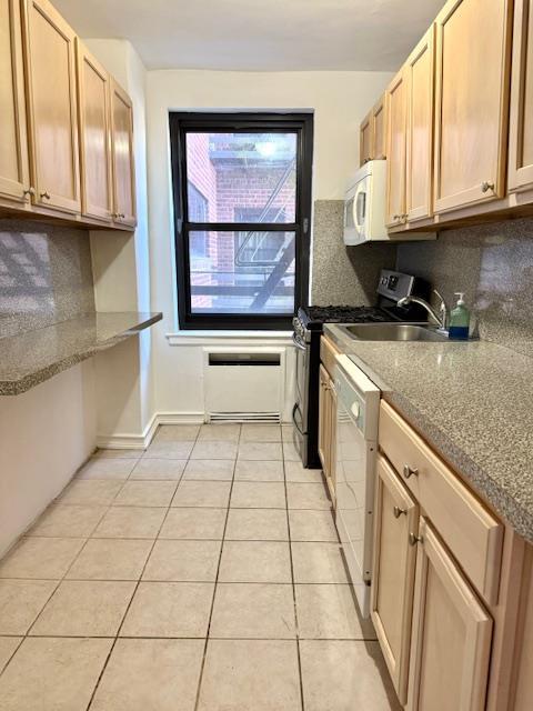 kitchen with white appliances, light tile patterned flooring, tasteful backsplash, and a sink