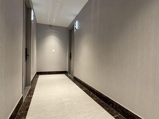 corridor with baseboards and marble finish floor