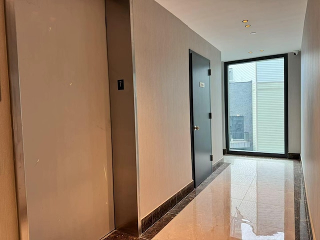 corridor featuring baseboards, elevator, marble finish floor, and floor to ceiling windows