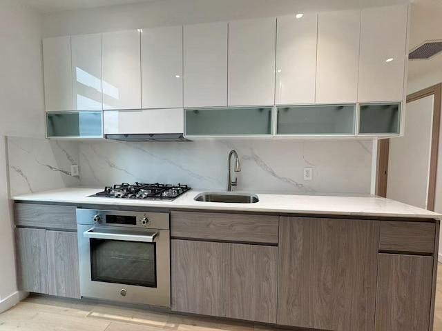 kitchen featuring tasteful backsplash, visible vents, a sink, stainless steel appliances, and modern cabinets