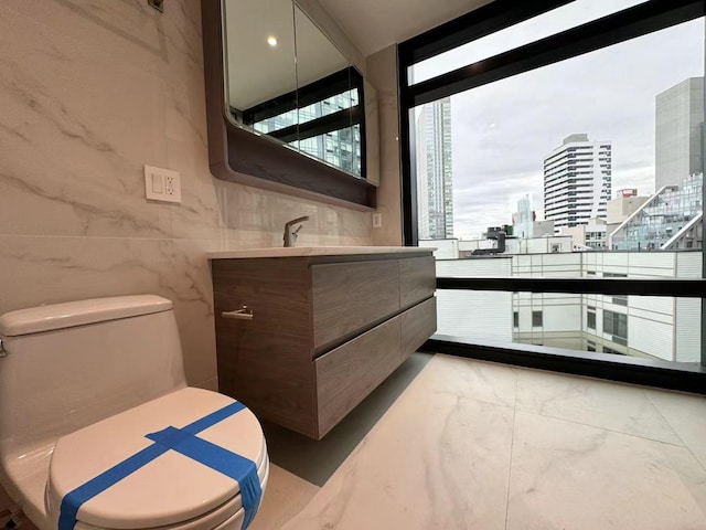 bathroom featuring a city view, toilet, vanity, and marble finish floor