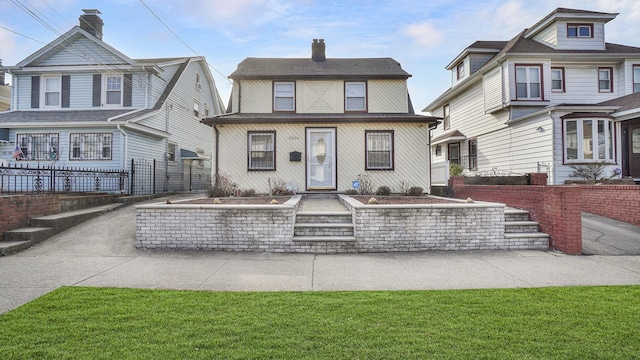 view of front facade featuring a front yard, fence, and a chimney