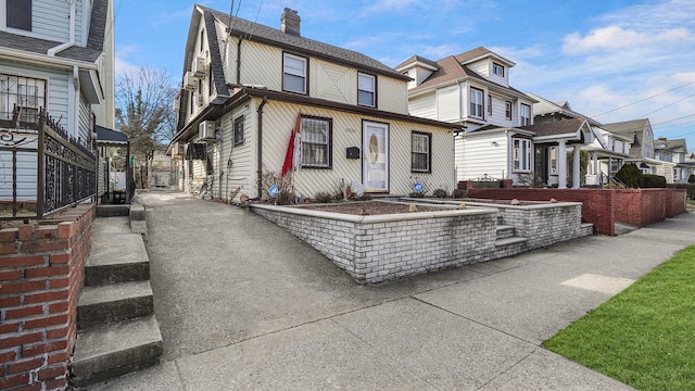 view of front of house with a residential view, a gambrel roof, and a chimney