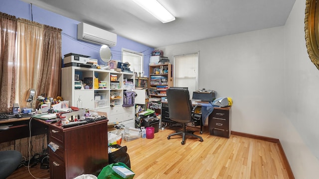 home office featuring an AC wall unit, wood finished floors, and baseboards