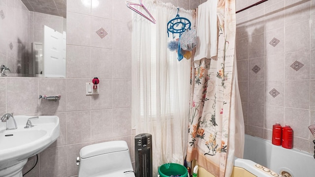 full bathroom featuring toilet, tile walls, shower / tub combo with curtain, and a sink