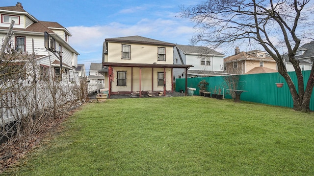 rear view of property featuring a fenced backyard and a yard