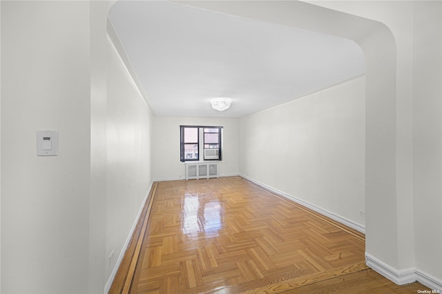 spare room featuring baseboards and arched walkways