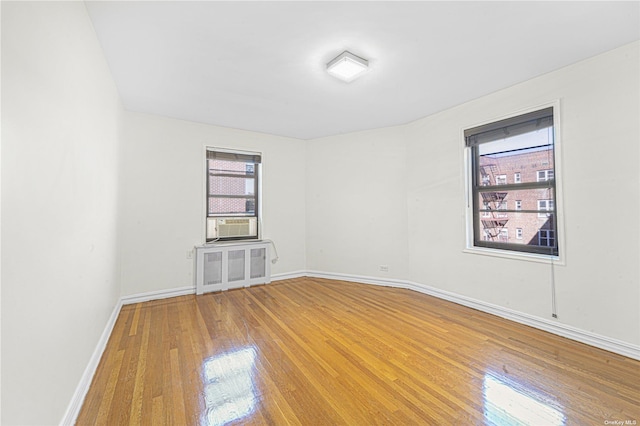 empty room with hardwood / wood-style floors, cooling unit, and baseboards