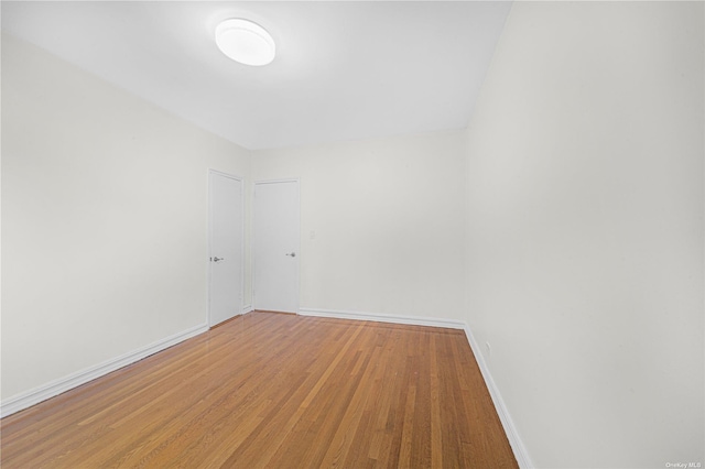 spare room with baseboards and light wood-style flooring