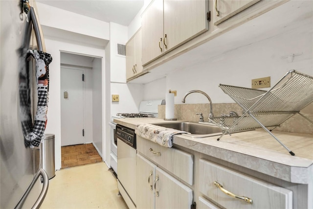 kitchen featuring visible vents, a sink, freestanding refrigerator, light countertops, and dishwashing machine