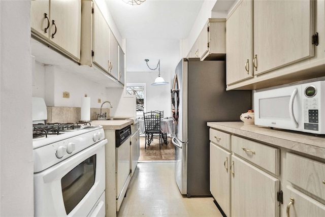 kitchen with hanging light fixtures, white appliances, light countertops, and a sink