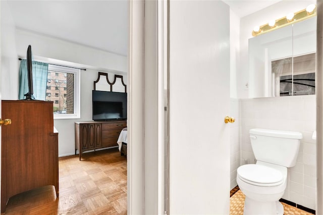 ensuite bathroom with ensuite bathroom, toilet, and tile walls