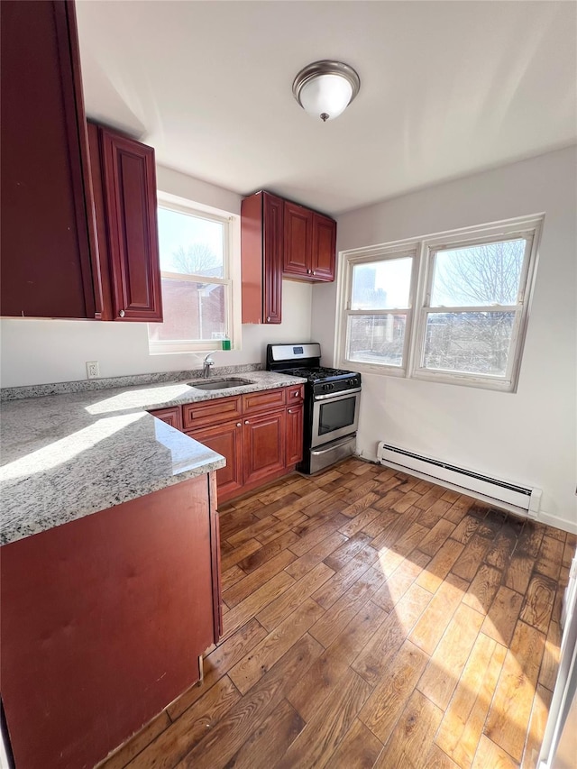 kitchen featuring a sink, dark brown cabinets, gas range, baseboard heating, and wood-type flooring