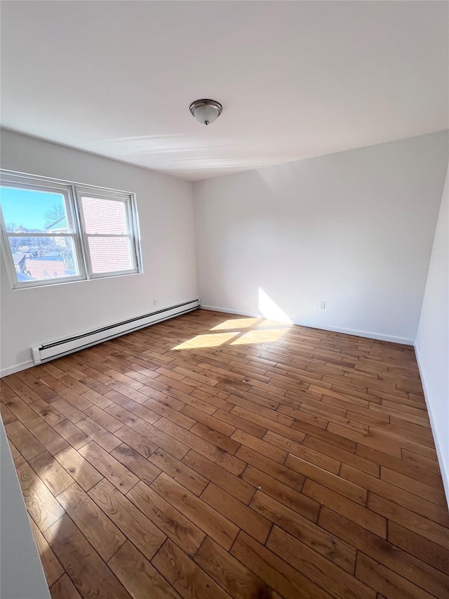 empty room featuring baseboard heating and wood finished floors