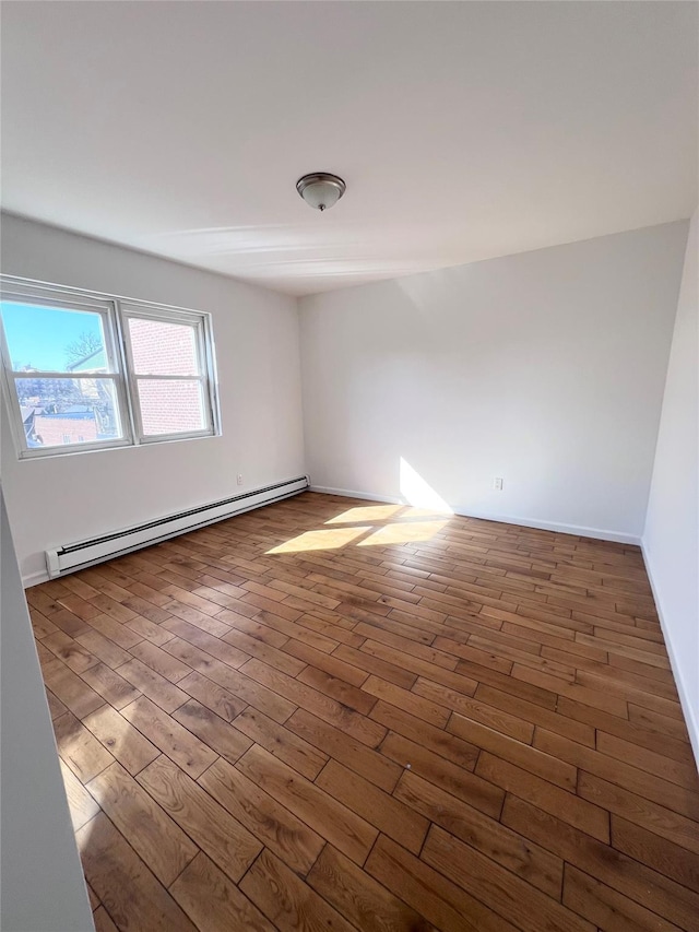 spare room featuring baseboard heating and wood finished floors