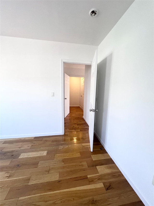 spare room featuring baseboards and wood finished floors