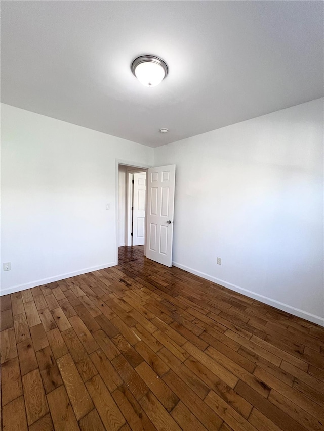 unfurnished room featuring baseboards and dark wood-type flooring